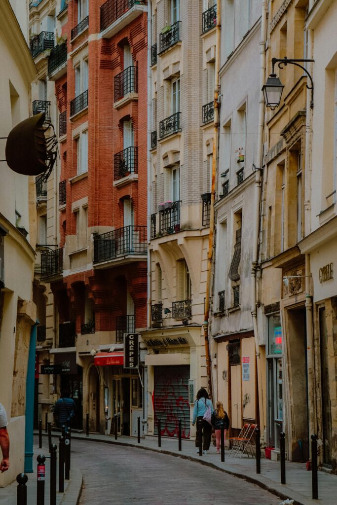 pexels-photo-14448249-14448249 A picturesque street in Paris's Marais district featuring classic architecture and pedestrians on the sidewalk.